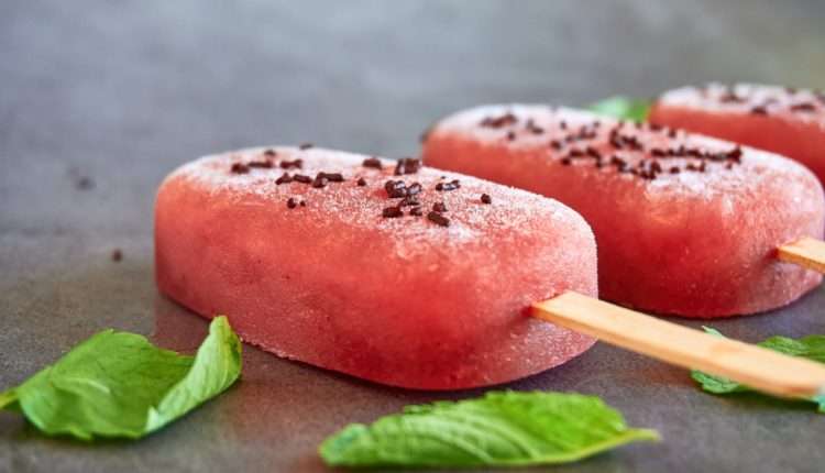 watermelon popsicles and mint leaves on gray table