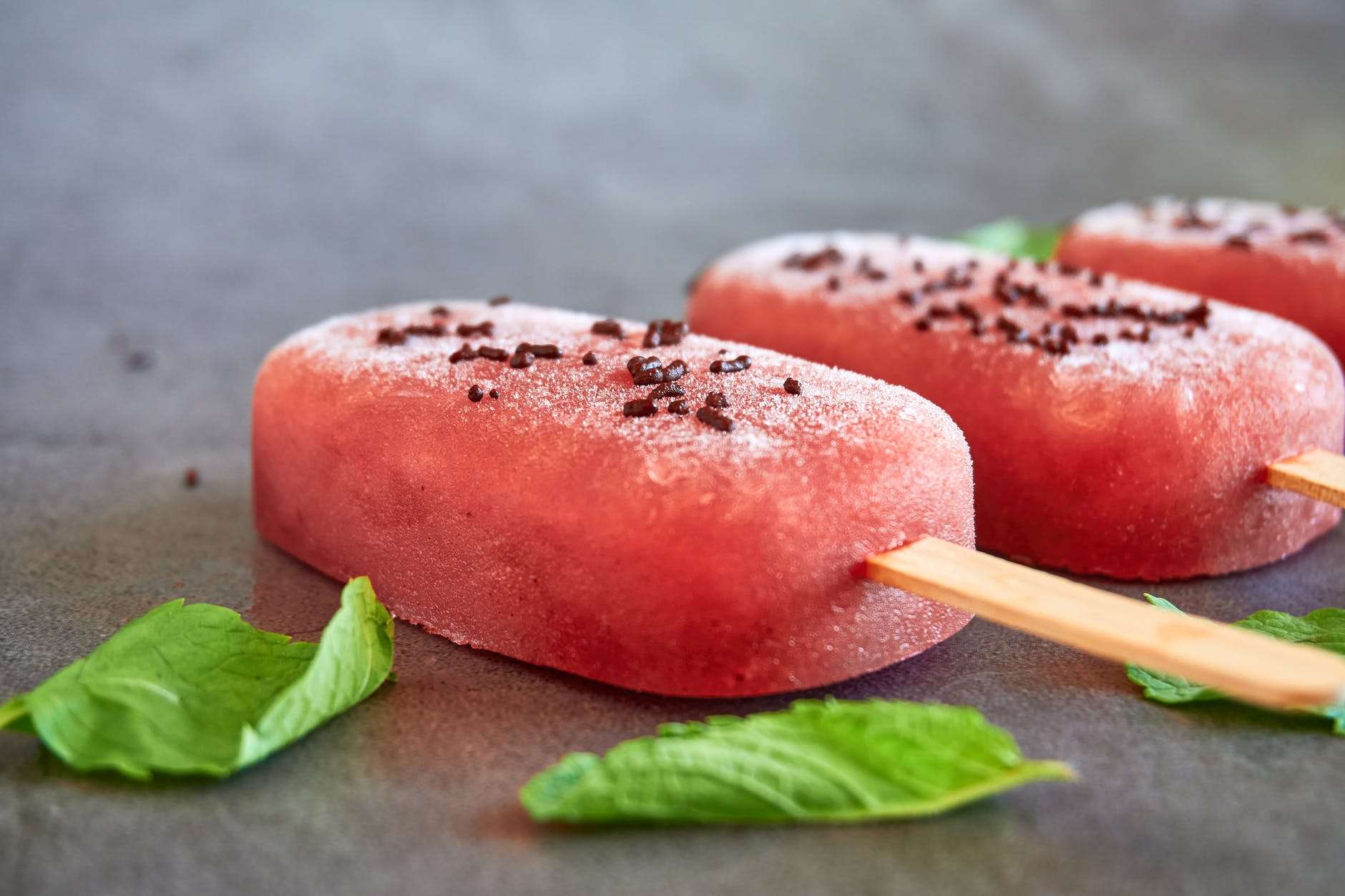 watermelon popsicles and mint leaves on gray table