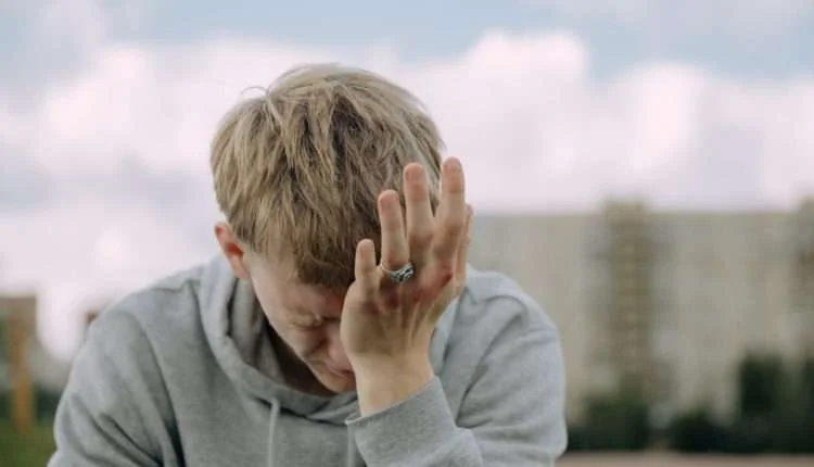 a man with bruised knuckles having a headache